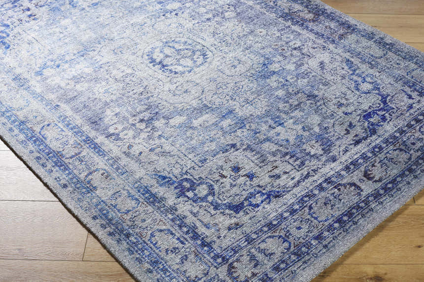 Close-up of the Csilla Area Rug. Traditional blue and ivory pattern on a hand-tufted polyester rug. Corner