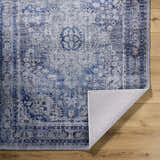 Close-up of the hand-tufted Csilla Area Rug. Traditional design in arctic sky, blue, ivory, and slate blue on wood floors. Fold