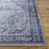 Close-up of the Csilla Area Rug. Hand-tufted polyester rug in arctic sky, blue, ivory, and slate blue on a wood floor. Front