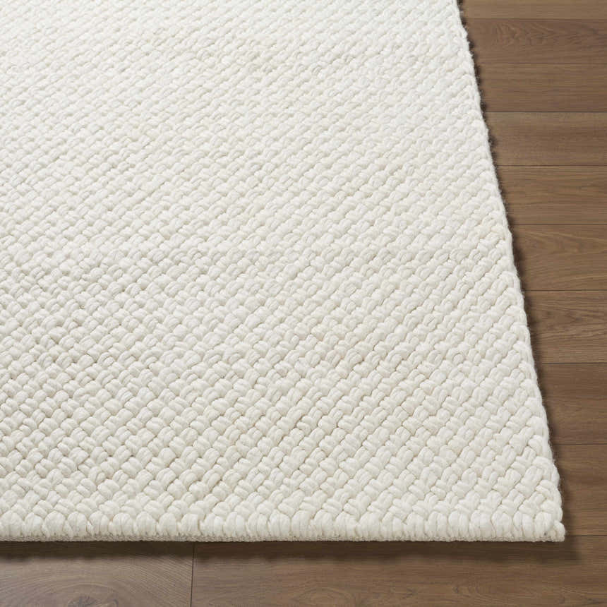 Close-up of the textured Cqasce Navy Solid Hand Woven Wool Area Rug in off-white on a wood floor. Front