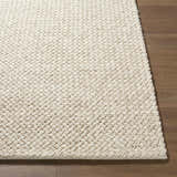 Close-up of the hand woven texture of the Rowue Ivory Solid Wool Area Rug on hardwood floor. Farmhouse style. Front