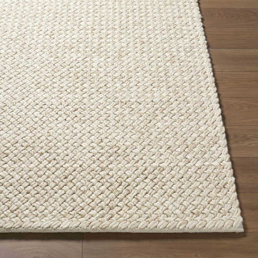 Close-up of the hand woven texture of the Rowue Ivory Solid Wool Area Rug on hardwood floor. Farmhouse style. Front