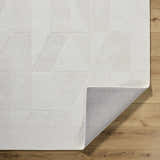 Close-up of the ivory Callie Area Rug showing geometric pattern, wool texture, and gray backing on wood floor. Fold