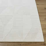 Close-up of the ivory Callie Area Rug showing its geometric pattern and hand-loomed wool texture on hardwood floor. Front