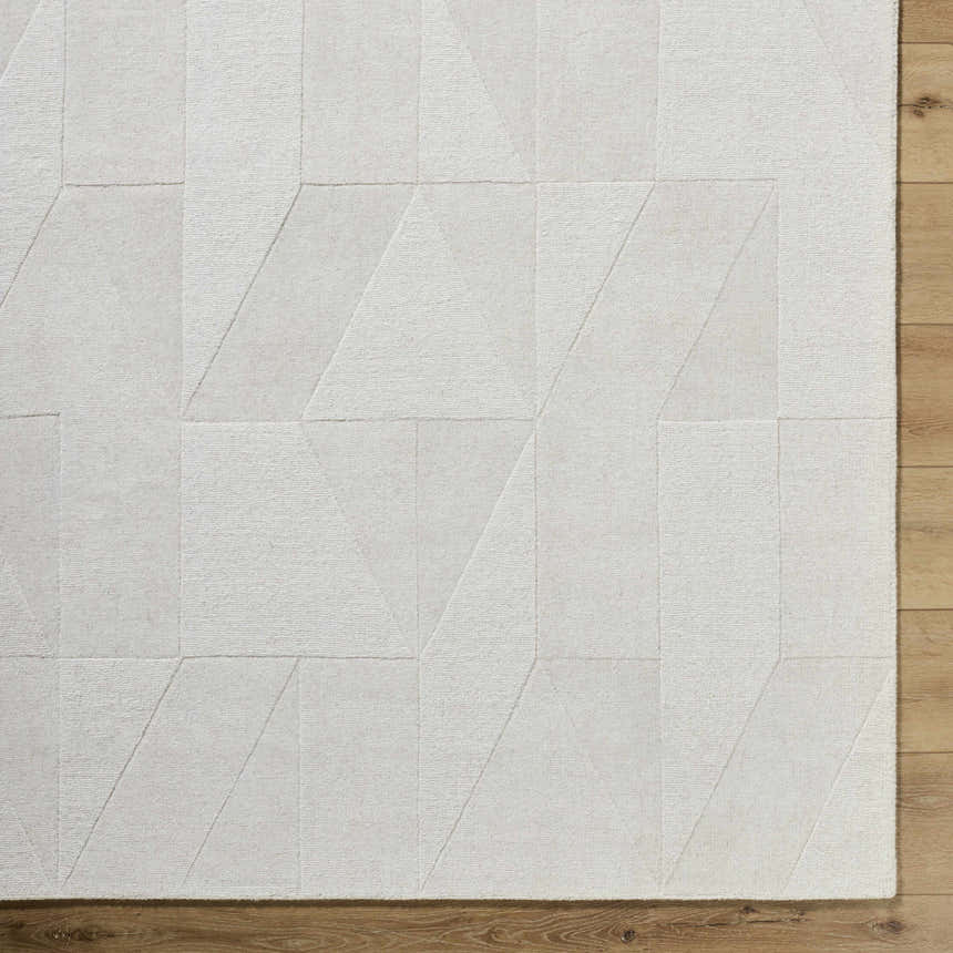 Close-up of the ivory Callie Area Rug. Hand-loomed wool rug with a geometric pattern and subtle texture. Corner