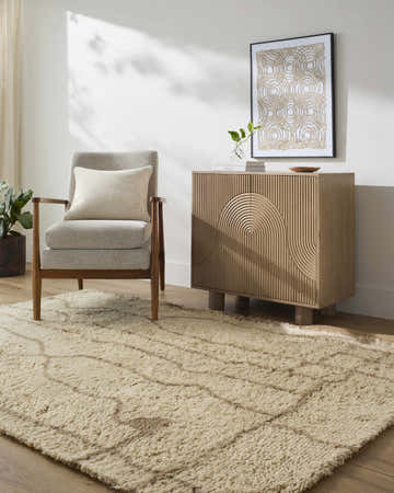 Living room scene with a beige Chesna area rug, gray chair, and sandstone cabinet. Roomscene-Rectangle