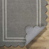 Close-up of the hand-tufted Chogan Stone Gray Area Rug showing wool texture, striped border, and scalloped edge. Fold