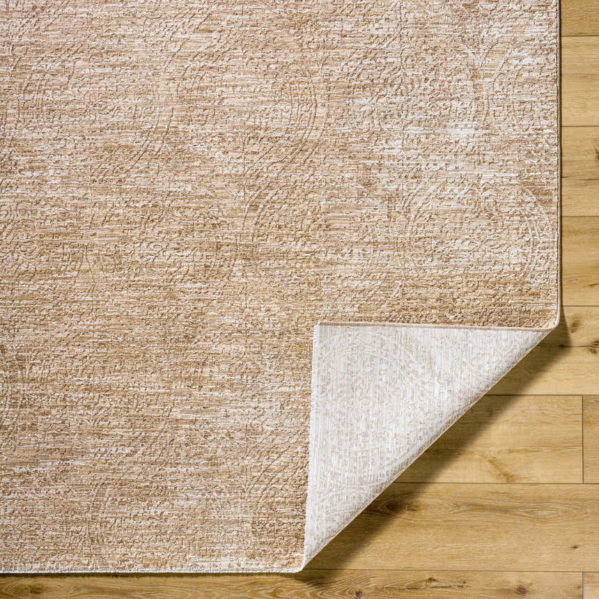 Close-up of the Cariel Beige Area Rug showing its textured, traditional pattern and tan, prairie dust colors on wood floor. Fold