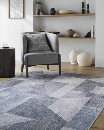 Living room scene with gray chair on Chachi Washable Geometric Rug in gray, light gray, navy, and slate blue. Roomscene-Rectangle