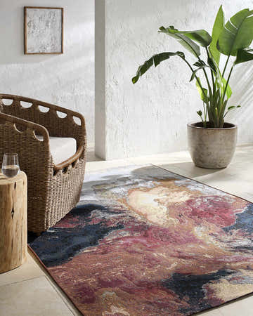 Coastal living room scene with a Chemed Area Rug in charcoal, crimson, and ivory. Wicker chair and potted plant add to the relaxed vibe. Roomscene-Rectangle