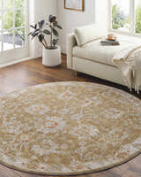 Sunlit reading nook with a round Castlegar rug in beige, red, and white floral pattern on wood floor. Cream chaise lounge. Roomscene-Round