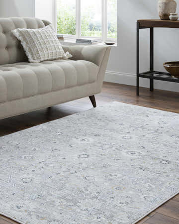 Living room scene with a light silver Cheyne Area Rug, beige sofa, and wood floors. Roomscene-Rectangle