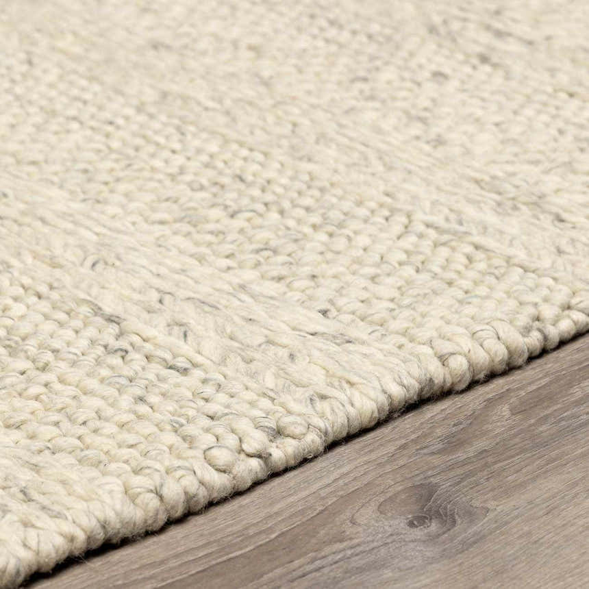 Close-up of a textured, hand-woven Clarke Textured Braided Stripe - Dark Beige Area Rug on wood floor. Pile