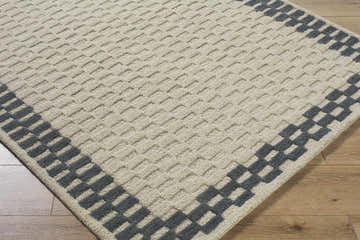 Close-up of the hand-tufted Camdyn Area Rug. Charcoal and ivory wool rug with a geometric pattern and textured weave. Corner