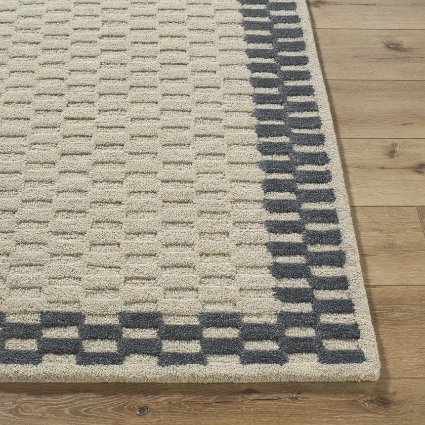 Close-up of the Camdyn Area Rug. Ivory rug with a charcoal geometric border on hardwood floor. 100% wool, hand tufted. Front