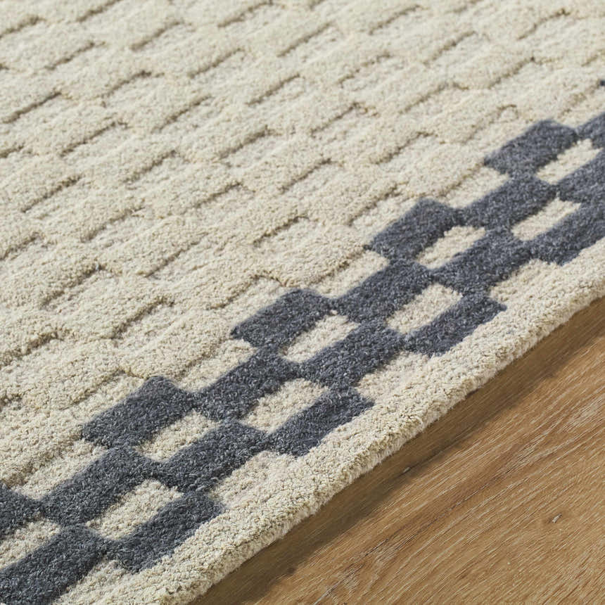 Close-up of the hand-tufted Camdyn Area Rug. Ivory wool rug with a charcoal geometric pattern. Contemporary style. Texture