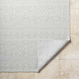 Close-up of the light silver Choire Area Rug featuring a contemporary diamond pattern and machine woven texture. Fold