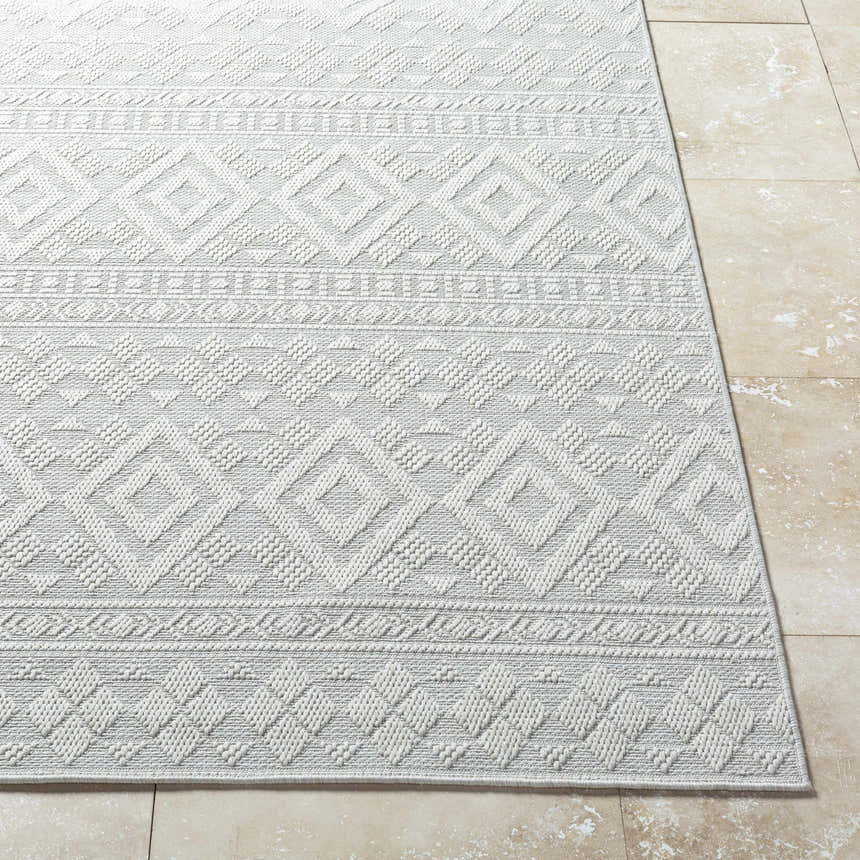 Close-up of the light silver Choire Area Rug showing its geometric diamond pattern and textured, machine-woven construction. Front