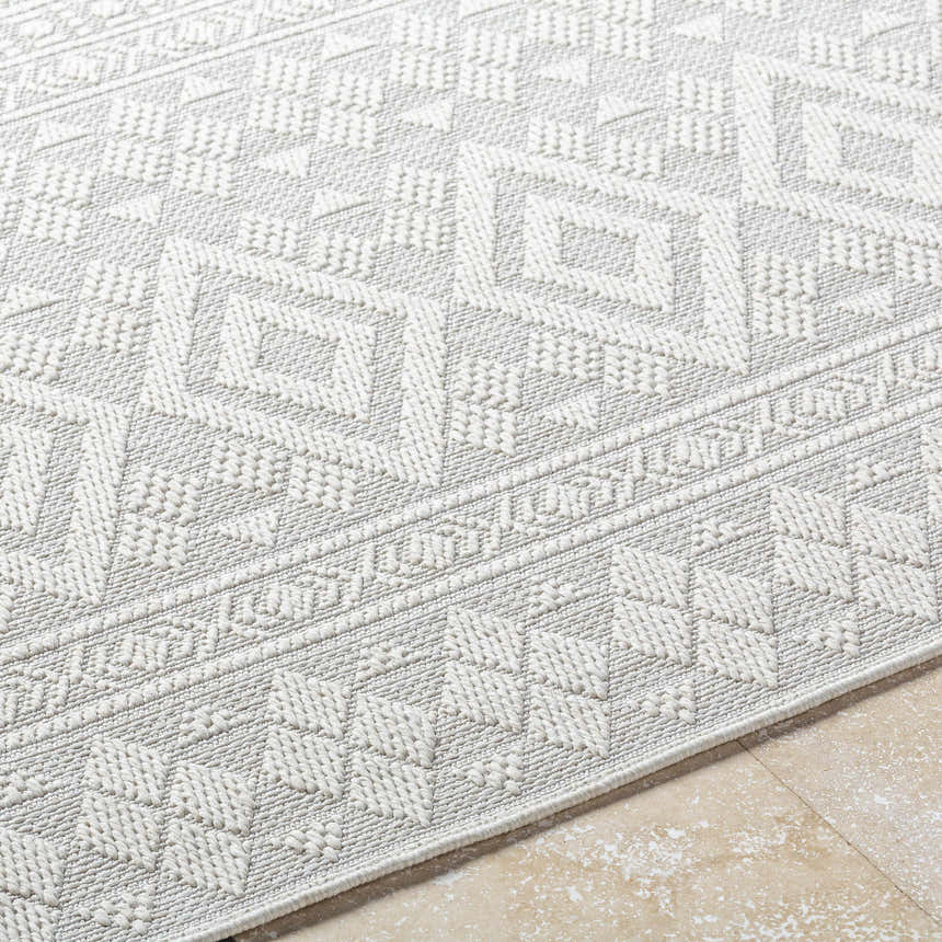 Close-up of the light silver Choire Area Rug, showcasing its geometric pattern and woven texture. Texture