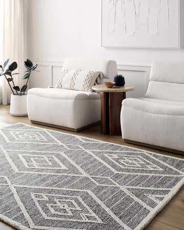 Living room scene with gray and off white Ceanna Area Rug, two white armchairs, wood side table, and neutral decor. Roomscene-Rectangle
