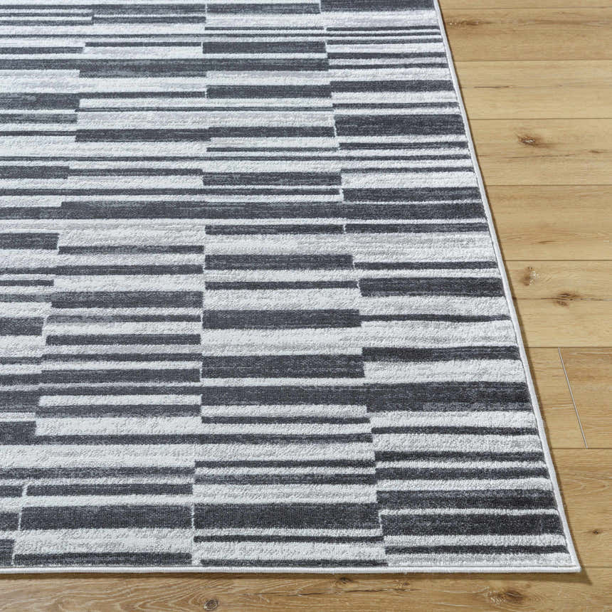 Close up of the Cemach Cream Area Rug showing a modern gray and white horizontal block pattern on wood flooring. Front