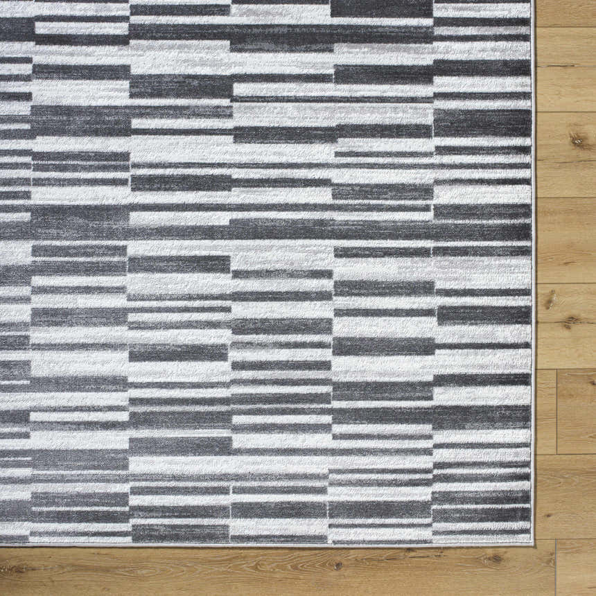 Close-up of the Cemach Cream Area Rug featuring a contemporary gray and white geometric pattern on wood floors. Corner