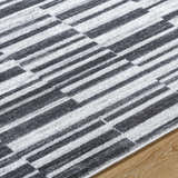 Close-up of the Cemach Cream Area Rug. Features a contemporary charcoal and silver gray geometric pattern. Texture