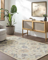 Living room scene with a cream Candid Oushak Area Rug, wood cabinet, potted plant, and neutral armchair. Roomscene-Rectangle