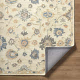 Close up of the hand-tufted Candid Oushak Area Rug. Cream wool rug with light brown and steel blue floral pattern. Fold