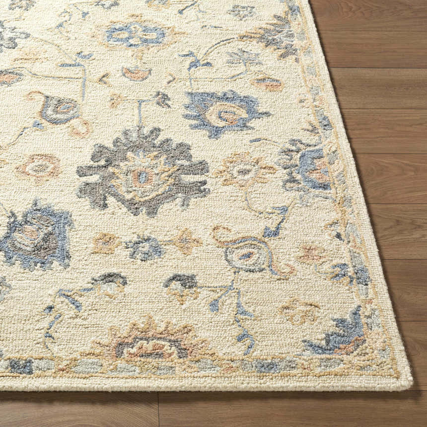 Close-up of the Candid Oushak Area Rug. Hand-tufted wool rug with cream, light brown, and steel blue floral pattern. Front