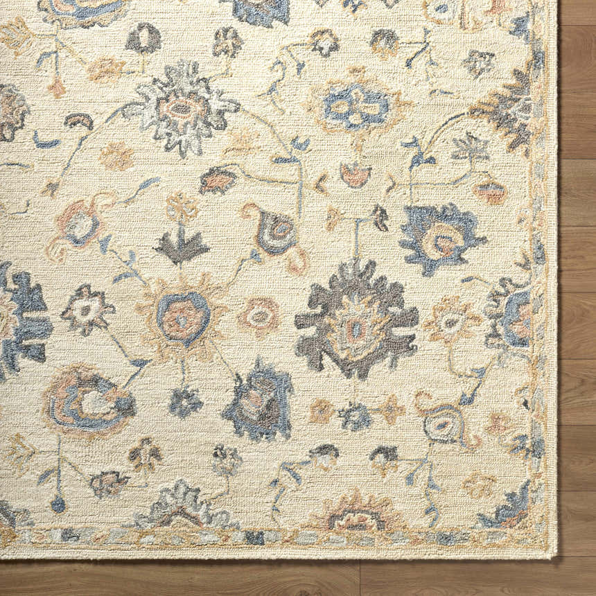 Close up of the Candid Oushak Area Rug. Cream wool rug with light brown and steel blue floral pattern. Corner