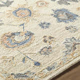 Close-up of the Candid Oushak Area Rug showing its cream, light brown, and steel blue floral pattern and hand-tufted wool texture. Texture