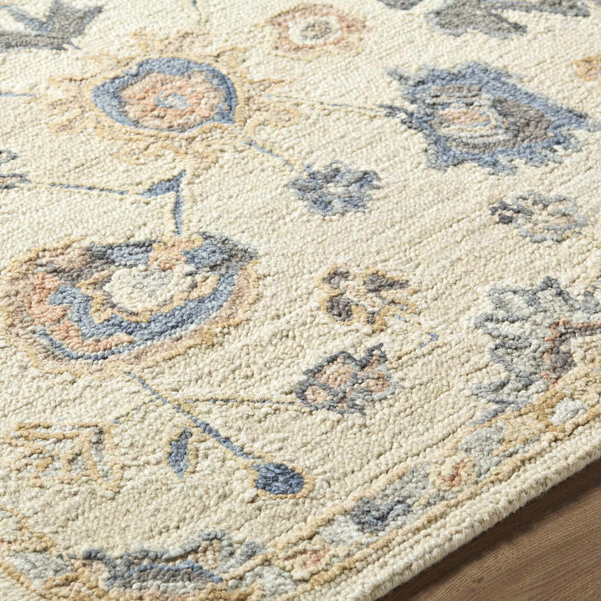 Close-up of the Candid Oushak Area Rug showing its cream, light brown, and steel blue floral pattern and hand-tufted wool texture. Texture
