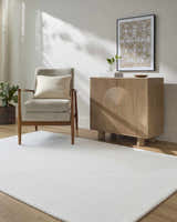 Living room scene with a Carpus Area Rug, gray chair, and light wood cabinet. Modern, neutral tones. Roomscene-Rectangle