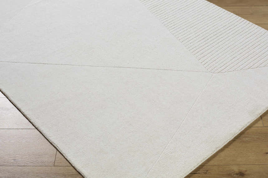 Close-up of the Carpus Area Rug. Ivory and light gray wool rug with geometric pattern and textured stripes. Corner