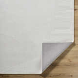 Close-up of the hand-loomed Carpus Area Rug in ivory, light gray, and pearl. Features a subtle geometric design. Fold