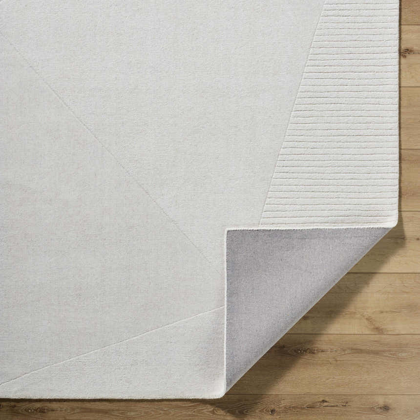 Close-up of the hand-loomed Carpus Area Rug in ivory, light gray, and pearl. Features a subtle geometric design. Fold