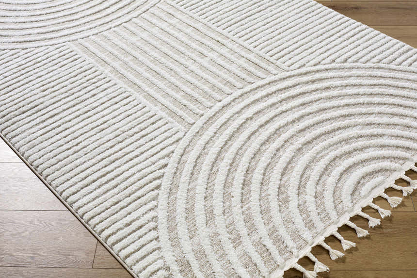 Close-up of the cream and peach Cassie Area Rug featuring a modern geometric design and tassels. Corner