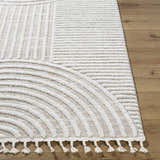 Close up of the Cassie Area Rug featuring a cream geometric design and braided tassels. Front