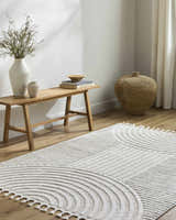 Minimalist living room scene with a cream Cassie Area Rug, wood bench, and neutral decor. Roomscene-Rectangle