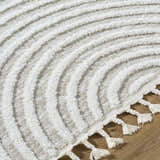 Close up of the Cassie Area Rug featuring cream and peach hues, textured lines, and tassel details. Texture