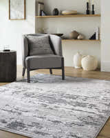 Living room scene with gray chair on Candie Gray Area Rug, wood floors and shelves with neutral decor. Roomscene-Rectangle