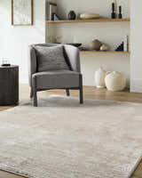 Living room scene with a gray chair on a Candie Beige Area Rug. The rug has a subtle contemporary design. Roomscene-Rectangle