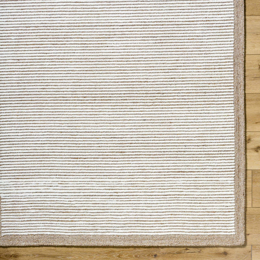 Close-up of the hand-tufted Cianna Area Rug. Beige and ivory stripes on a 100% wool rug with a tan border. Corner
