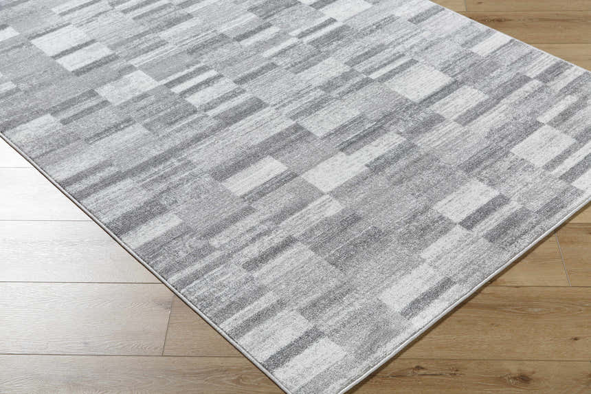 Close-up of the Cherie Medium Gray Area Rug featuring a contemporary light silver and gray geometric pattern. Corner