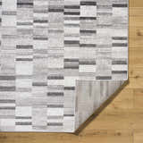 Close up of the Cherie Cream Area Rug showing its gray, light silver, and sage geometric pattern and texture. Fold