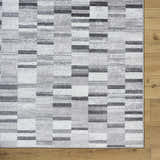 Close-up of Cherie Cream Area Rug showing a contemporary gray, light silver, and sage block pattern. Corner
