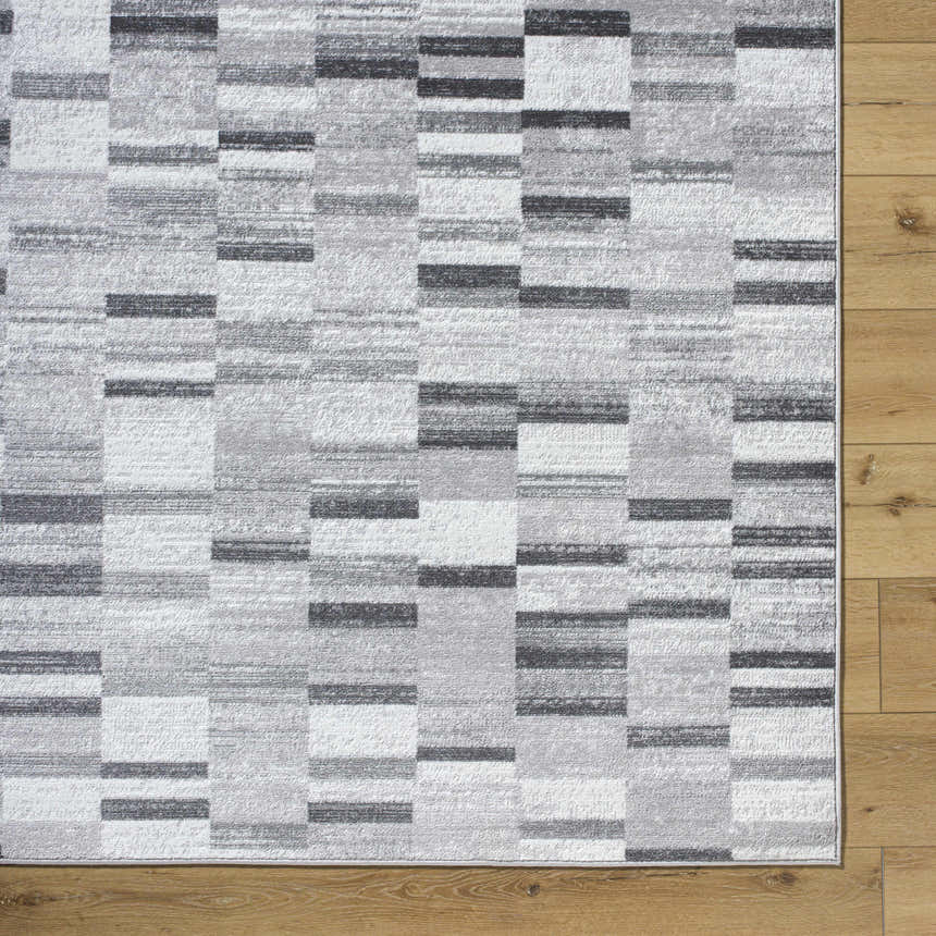 Close-up of Cherie Cream Area Rug showing a contemporary gray, light silver, and sage block pattern. Corner