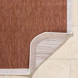 Close-up of the Chetan Brown Outdoor Rug showing its woven texture, cream border, and polypropylene backing. Fold
