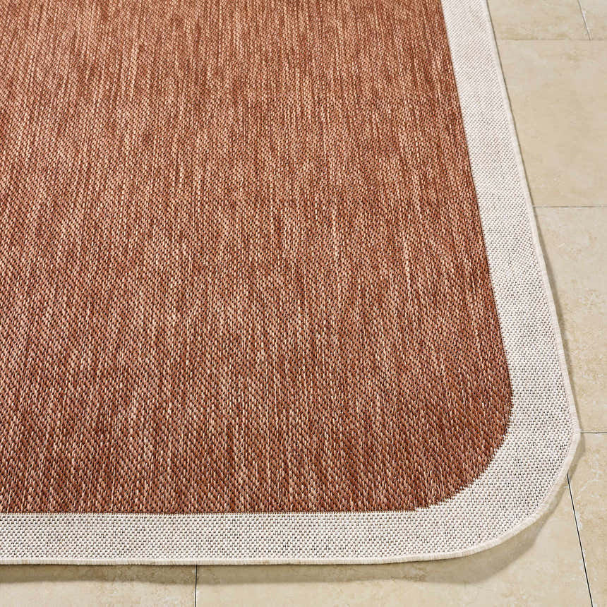 Close-up of Chetan Brown outdoor rug showing woven texture, brown and cream colors, and rounded corner. Front
